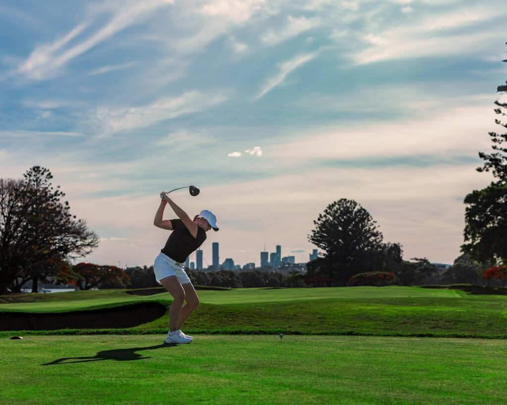 A golfer swinging on a green fairway